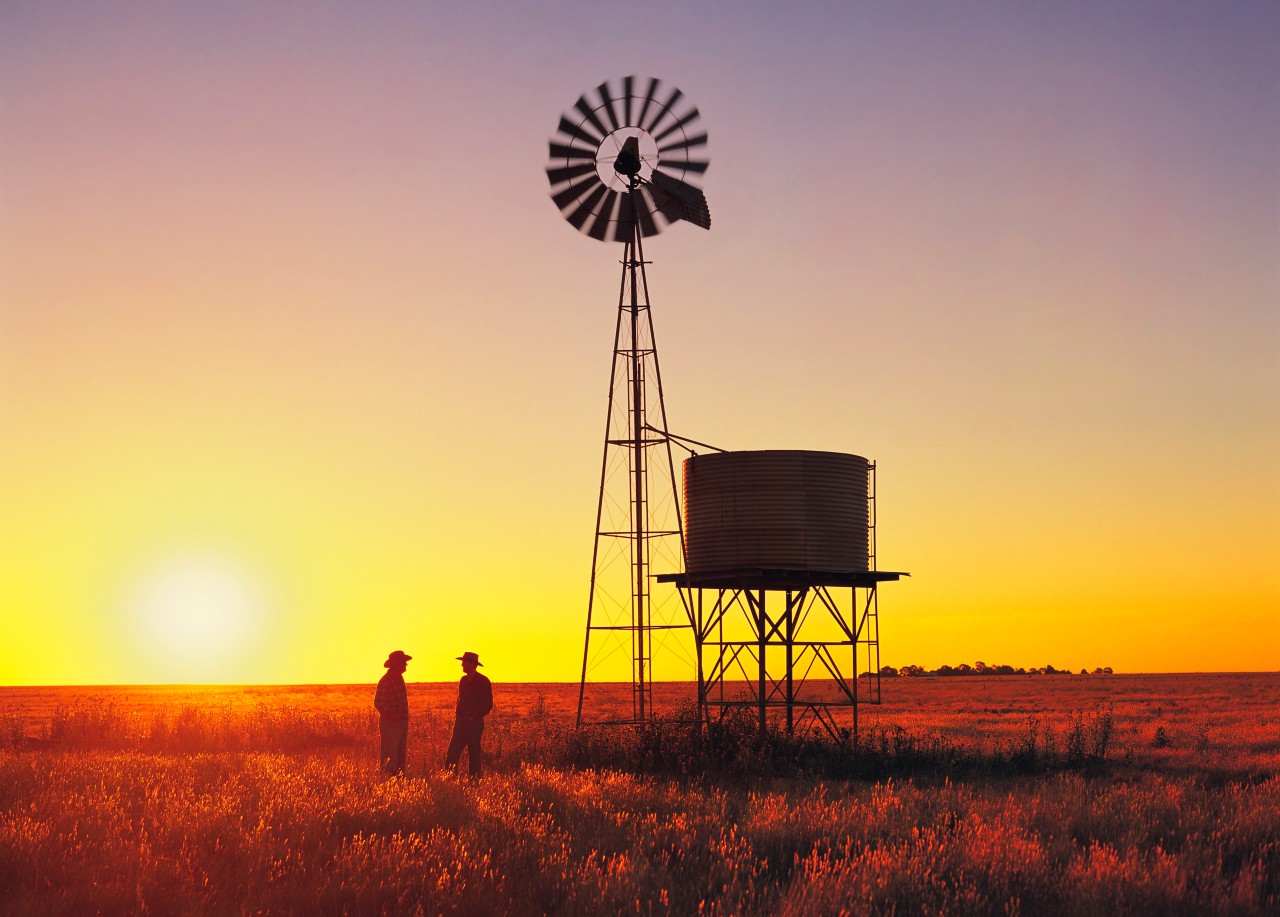Wheat farmers talking beside windmill, watertank, sunset, Australia, water supply