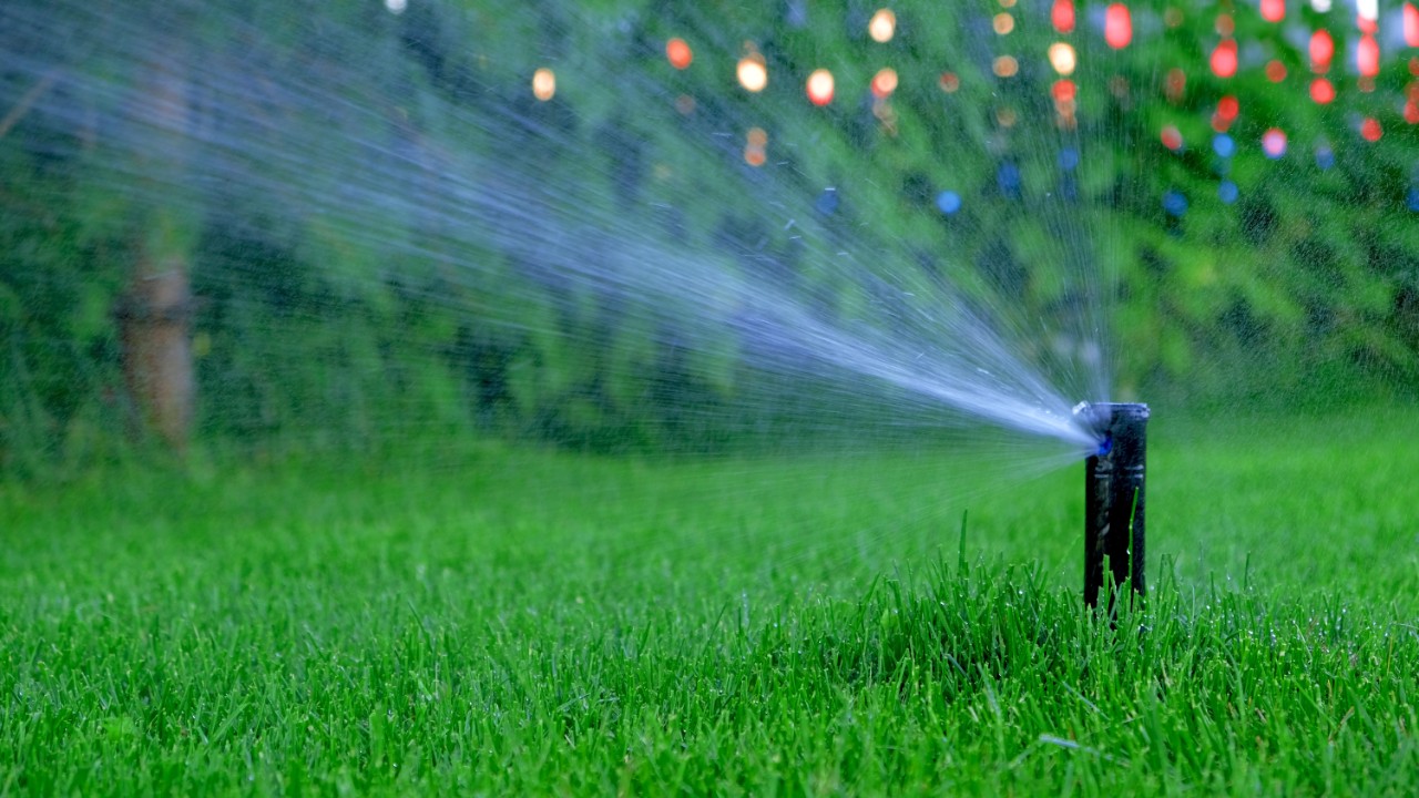 Automatic garden irrigation system watering lawn. Savings of water from sprinkler irrigation system with adjustable head. Automation for lawn irrigation, gardening, soccer fields or golf courses.