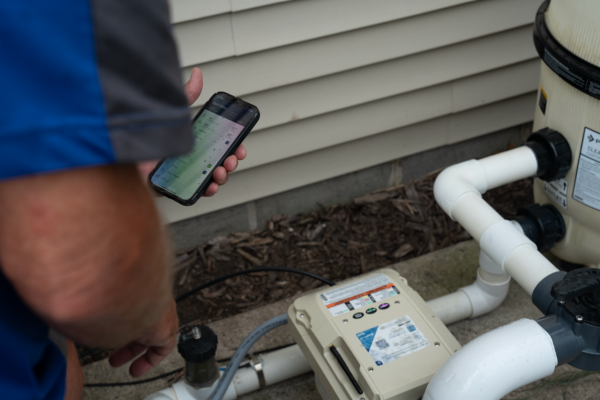 pool owner controlling IntelliFlo3 using phone by pump at the equipment pad in Ham Lake, MN
