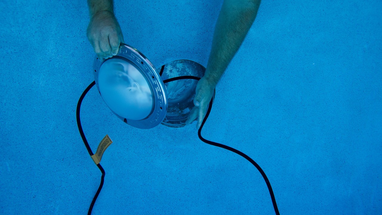 Someone installing IntelliBrite Pool Light into underground pool