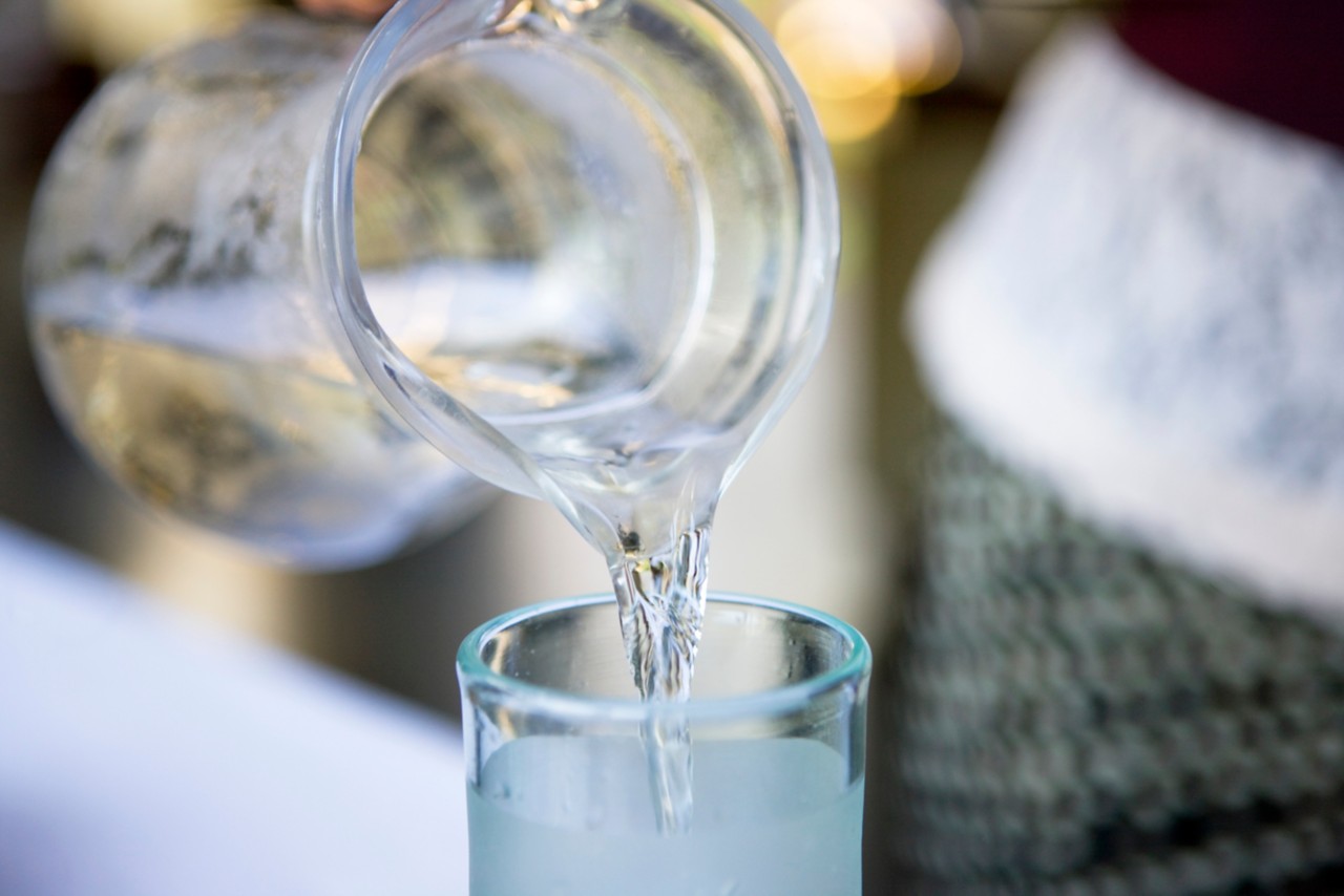 Closeup pouring water from pitcher into glass, drinking water, water filtration, pure water